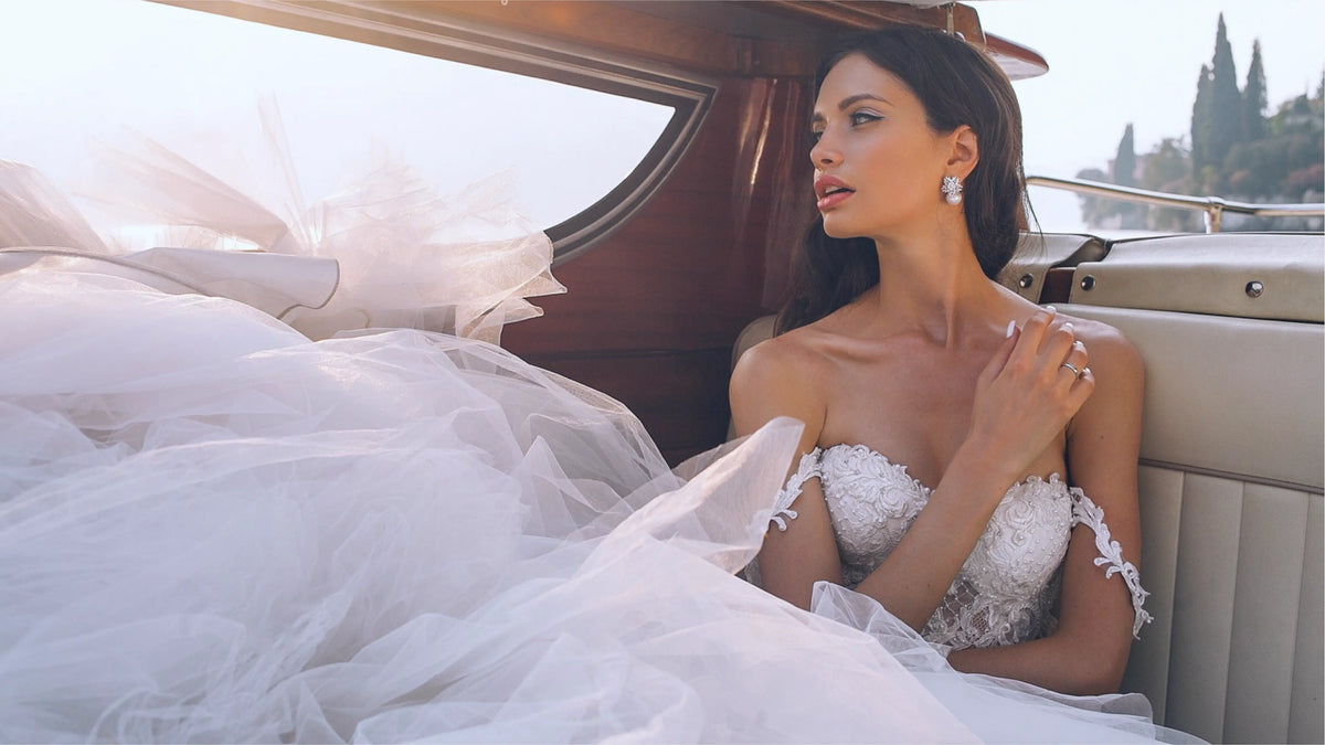 Bride in an off-shoulder lace wedding gown wearing sparkling drop earrings and a ring, Calilo Australia bridal jewellery