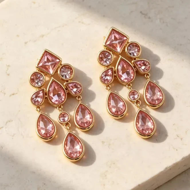 Calilo Australia chandelier earrings featuring pink crystals in a polished gold-tone frame with geometric drop shapes.