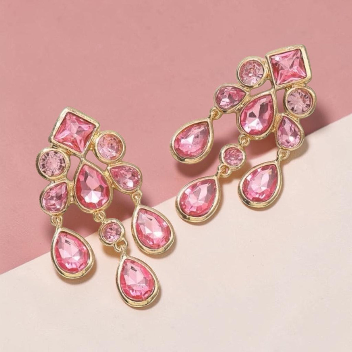 Calilo Australia statement chandelier earrings featuring pink crystals in a polished gold-tone geometric drop design.